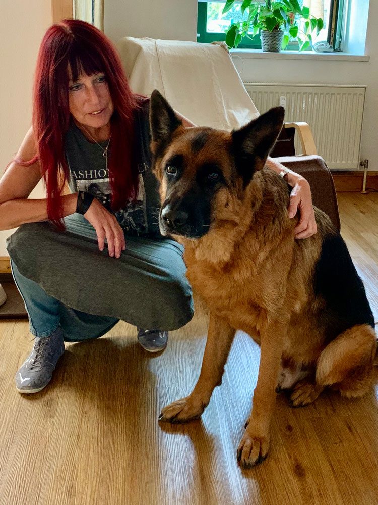Portrait von Cornelia Köhler mit einem Deutschen Schäferhund in ihrer Praxis